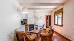 a living room with leather chairs and a fireplace at Casa El Rancho Montecorto by Ruralidays in Montecorto