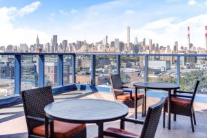 a balcony with tables and chairs and a view of the city at Vista LIC Hotel, Premier Collection by Best Western in Queens