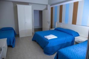 a bedroom with two beds with blue sheets at Hotel Al Rustico in Crosia