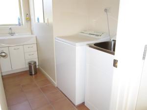 a small kitchen with a sink and a washing machine at Gladstone Cottage in Twizel