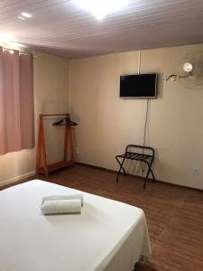 Una habitación con una cama y un televisor de pantalla plana. en Pousada Recanto do Arraial do Cabo, en Arraial do Cabo