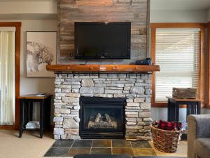 sala de estar con chimenea de piedra y TV de pantalla plana en Panorama Springs, en Panorama