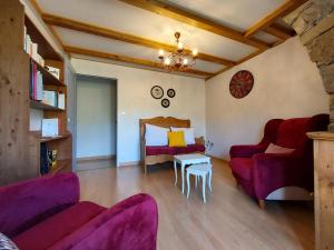 een woonkamer met paarse banken en een tafel bij Chambre d'hôtes LES LOUVES in Saint-Paul-des-Fonts