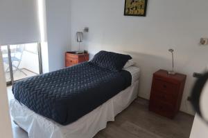a bed with a black comforter and a night stand at Hermoso departamento, excelente ubicación in Santiago