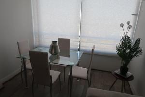 a dining room with a glass table and chairs and a window at Hermoso departamento, excelente ubicación in Santiago