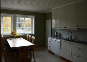 a kitchen with white cabinets and a table with chairs at Ljøra Lodge - Home of nature and peace - All year in Ljørdalen