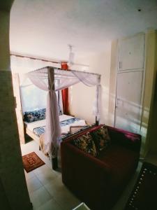 Ocean View Nyali Boutique Hotel في نيالي: غرفة نوم بسرير واريكة مع مظلة