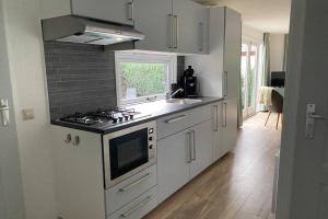 a white kitchen with a stove and a sink at Modern rustgevend chalet in Putten 131 in Putten