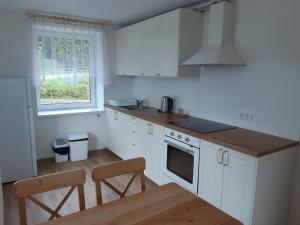 a kitchen with white cabinets and a table and a window at Apartmány U Zvoničky in Prachov
