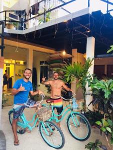 two men standing next to bikes in front of a building at Molar Wave in Himmafushi