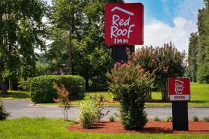 a red roof inn sign in a yard with bushes at Red Roof Inn Dahlgren - Naval Base in Dahlgren