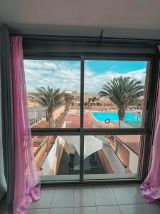 a window with a view of a swimming pool at A los Soles de Fuerteventura in Costa de Antigua