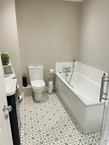 a white bathroom with a tub and a toilet at Luxurious Beach Front Apartment in Portrush in Portrush