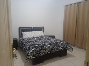a bedroom with a bed with a black and white comforter at Furnished room in a villa in town center. With private bathroom in Al 'Ayn