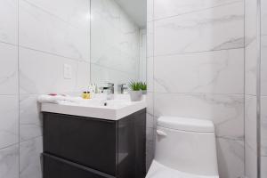 a white bathroom with a sink and a toilet at Fun & Funky Little Italy Studio with Full Kitchen by Den Stays in Montréal +57 photos