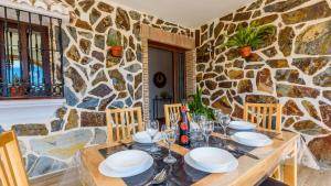 uma sala de jantar com uma mesa e uma parede de pedra em Villa Asuncion Arenas by Ruralidays em Arenas