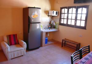 cocina con nevera, silla y mesa en Hostal Paseo de los Colorados en Purmamarca