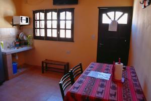 a kitchen with a table with a red table cloth and a door at Hostal Paseo de los Colorados in Purmamarca