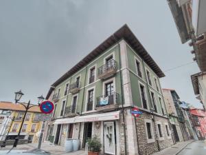 un edificio verde y blanco en una calle de la ciudad en THE COOL FLAT en Llanes