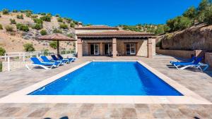 a swimming pool with chairs and a house at Casa El Hoyillo El Gastor by Ruralidays in El Gastor