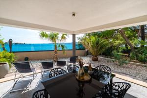 un tavolo da pranzo e sedie su un patio con vista sull'oceano di Marina-Bay-Resort a Sukošan (San Cassiano)