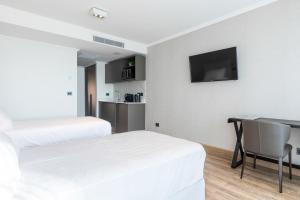 1 dormitorio con 2 camas, escritorio y TV en Hotel Solerios, en Punta del Este