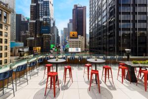 a rooftop patio with tables and red stools at M Social Hotel Times Square New York in New York
