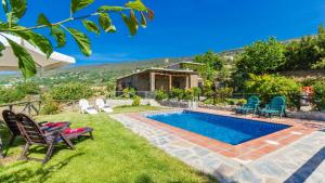 een achtertuin met een zwembad en stoelen bij Cortijo Noguera La Taha - Pitres by Ruralidays in Granada