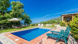 a swimming pool with blue chairs and a house at Cortijo Noguera La Taha - Pitres by Ruralidays in Granada