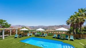 a swimming pool with lawn chairs and umbrellas at Finca Salrima Alora by Ruralidays in Alora