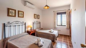 una camera da letto con due letti e una finestra di Casa La Pedrosa Setenil de las Bodegas by Ruralidays a La Cimada Altre 28 foto