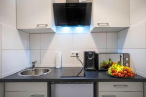 eine Küche mit einem Waschbecken und einer Schale mit Obst auf der Theke in der Unterkunft RüSuite II - Gemütliches Apartment in Rüttenscheid in Essen