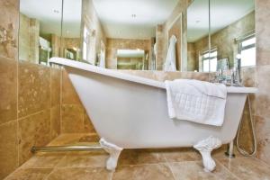 a large white bath tub in a bathroom at Cobo Bay Hotel in Castel +49 photos