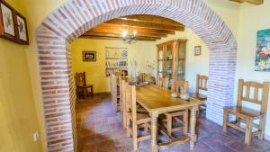 a dining room with a table and a brick archway at Casa Dona Vela Riogordo by Ruralidays in Ríogordo