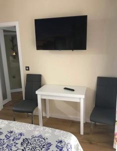 a white table with two chairs and a television on a wall at Suite Lugo in Úbeda