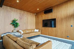 a living room with a couch and a tv at Kapiti Heights - Ōtaki Beach Holiday Home in Otaki Beach