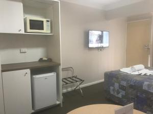 a small room with a bed and a microwave at Breeze Inn 13 Princes Highway, Ulladulla in Mollymook