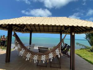 Sirinhaém的住宿－Casa Beira Mar - Guadalupe Gamela，海滩上草伞下的吊床