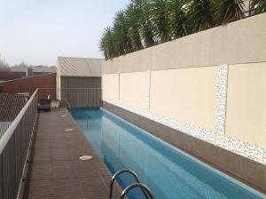 a swimming pool with a fence and palm trees at Newcastle Central Plaza Apartment Hotel Official in Newcastle