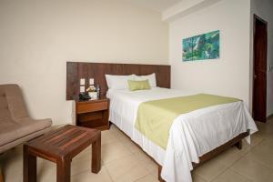 - une chambre dotée d'un lit, d'une chaise et d'un siège dans l'établissement Imperla Hotel, à Isla Mujeres