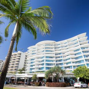 a large white building with a palm tree in front of it at Mantra Sirocco in Mooloolaba