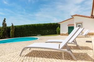 a patio with two chairs and a swimming pool at Holiday home in Ribamar - Lissabon Region 42000 in Ribamar