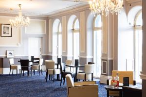 a dining room with tables and chairs and chandeliers at The Burlington Hotel in Eastbourne