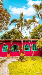 uma casa vermelha com palmeiras em frente em Woman Trip Hostel Boutique - Arraial d´Ajuda em Arraial d'Ajuda