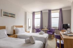 a hotel room with two beds and purple chairs at The Burlington Hotel in Eastbourne