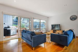 a living room with two blue chairs and a television at Our Escape at Rye - Modern Beachouse in Rye