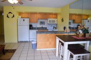 a kitchen with wooden cabinets and a white refrigerator at Kihei Kai Nani 161 in Kihei
