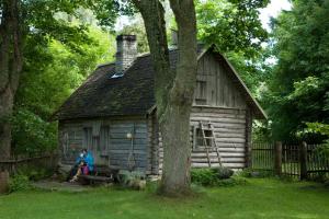 a person sitting on a bench in front of a cabin at Toomarahva Farmstay in Altja