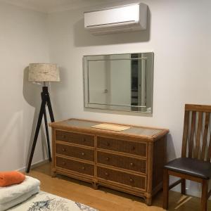 a bedroom with a dresser and a mirror on the wall at Oceanview Apartment in Airlie Beach