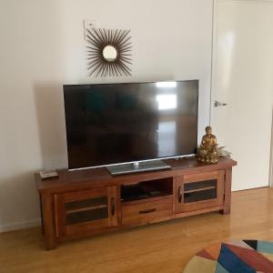 a flat screen tv sitting on top of a wooden entertainment center at Oceanview Apartment in Airlie Beach